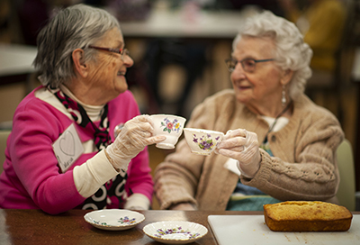 two older women holding tea cups and smiling